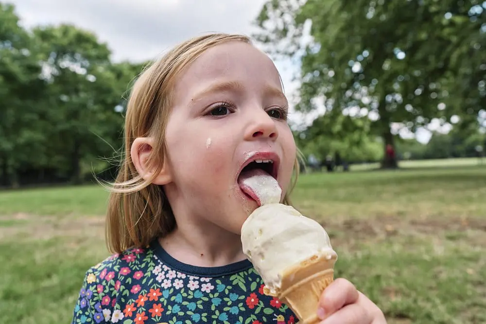 Child licking an ice cream in a London park — fun relaxed family photography London