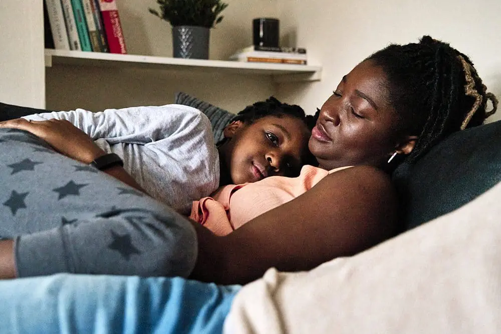 Here they are:
Son lying on mum resting together on the sofa — intimate candid family photography South-East London