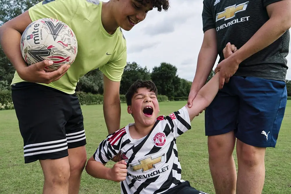 Brothers playing football together — candid childhood photography South-East London