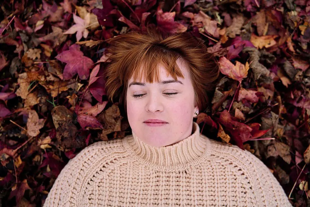 Woman lying in autumn leaves — creative personal brand photography session London