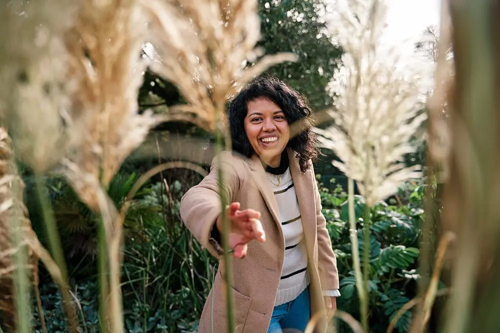 Photographer playfully half-hidden behind tall grasses — creative personal brand photography Kent