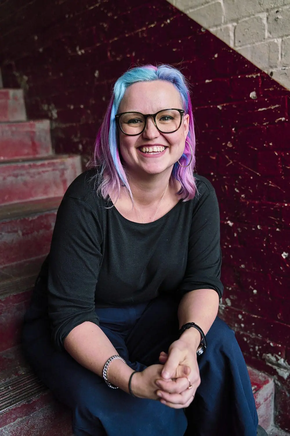 Creative professional sitting on stairs smiling confidently — relaxed headshot photographer London