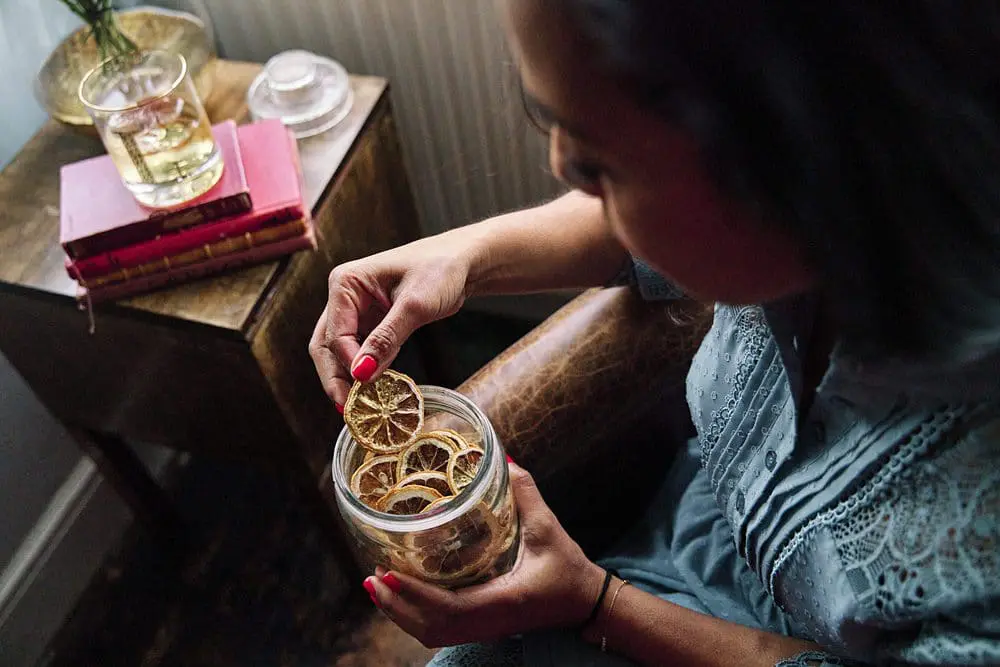 Woman taking dried orange from canister — behind the scenes brand photography London
