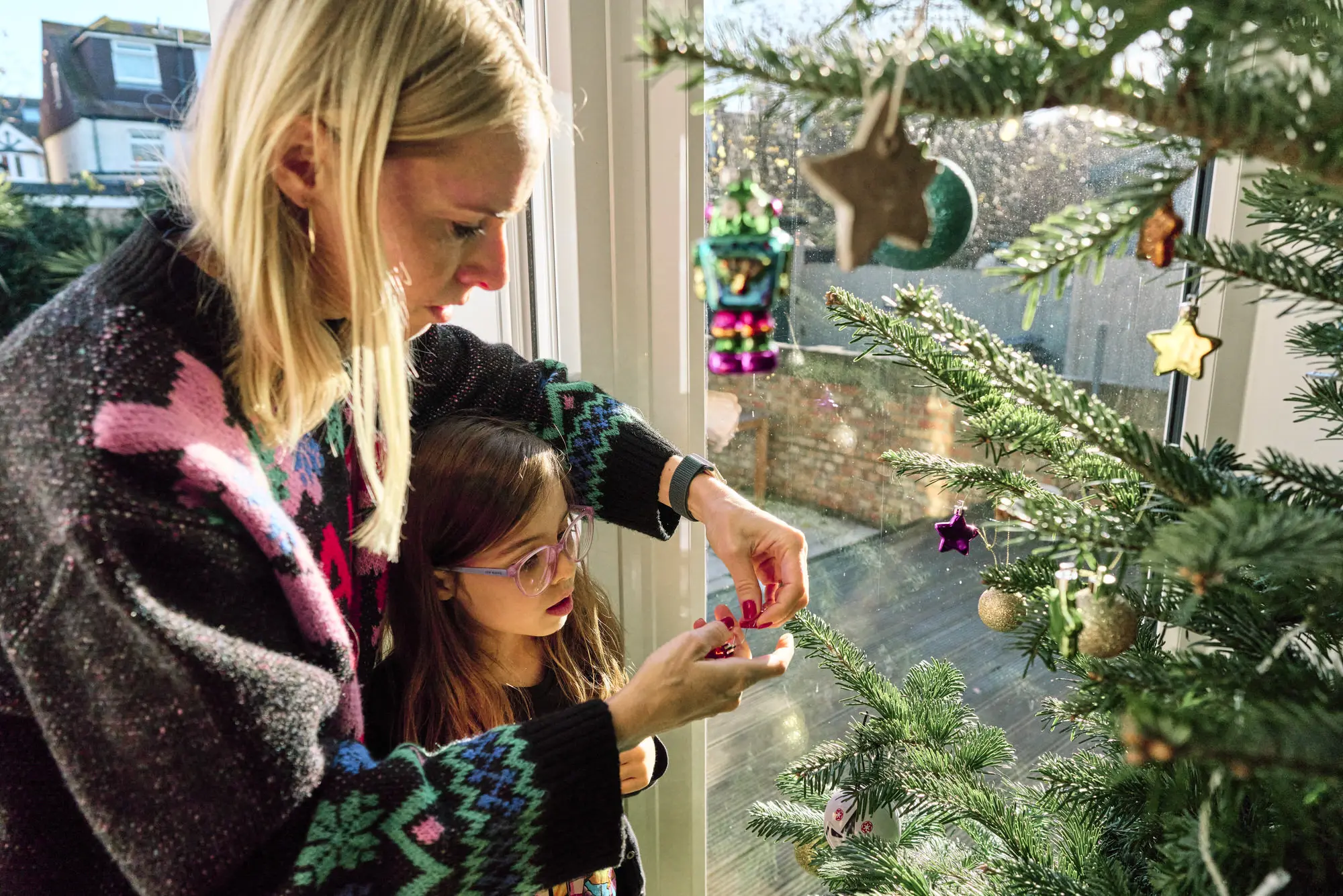 Mum and child decorating the Christmas tree together, natural and fun Christmas family photography in London