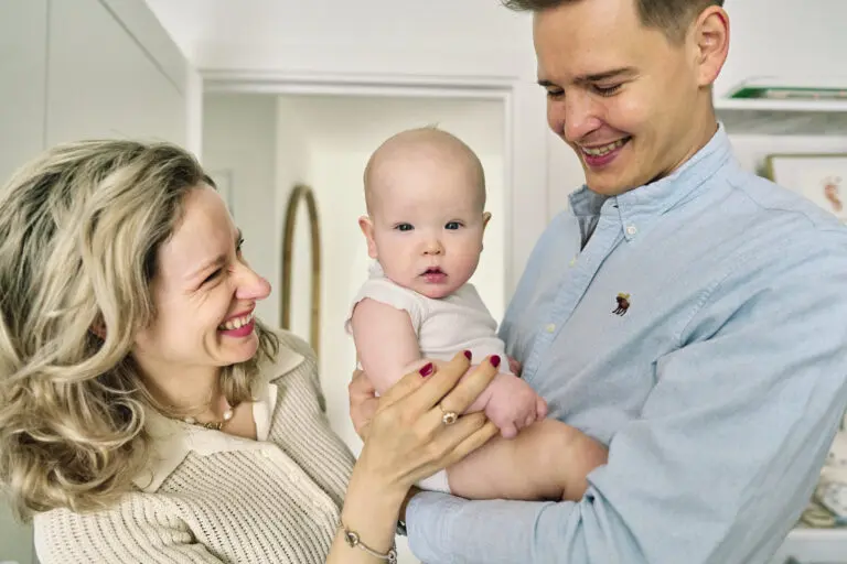 other and father holding their almost one-year-old baby during a relaxed family photo session at home.