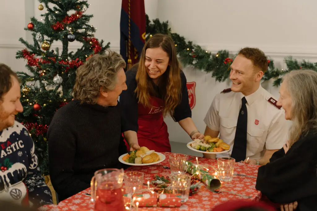 Salvation Army officer and volunteers serving Christmas dinner to guests — charity photographer for The Salvation Army