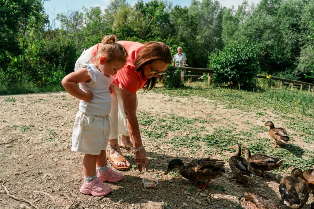 Grandmother and her toddler granddaughter feeding the ducks at a pond — kinship family documentary photography