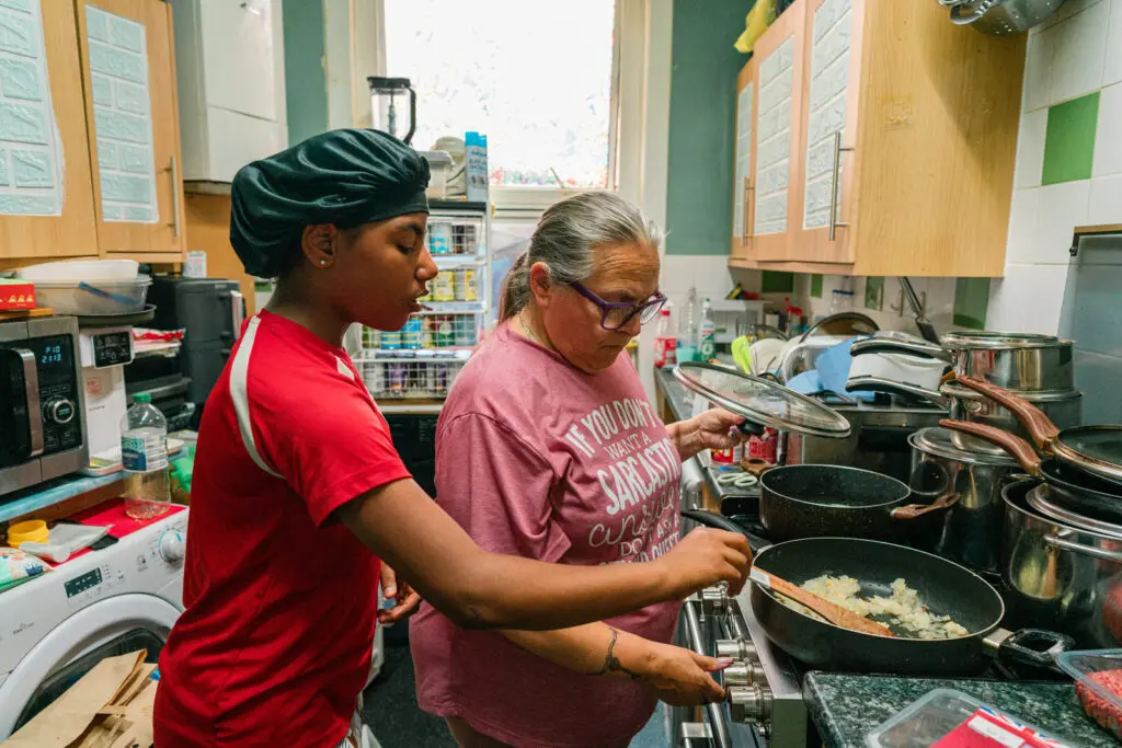 Grandmother and kinship carer cooking with her granddaughter in the kitchen — ethical charity photography UK