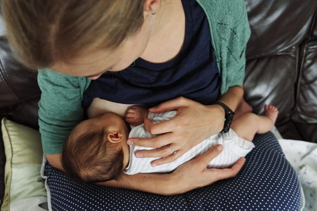 Mother feeding her newborn during a photoshoot of her baby.