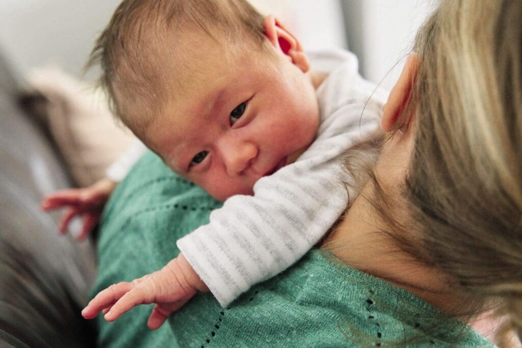 Baby being burped on the shoulder of mother during a newborn documentary family photoshoot.