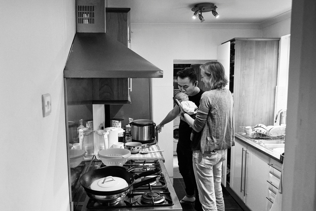 Photograph of father kissing his baby while cooking in Bromley during a photoshoot. 