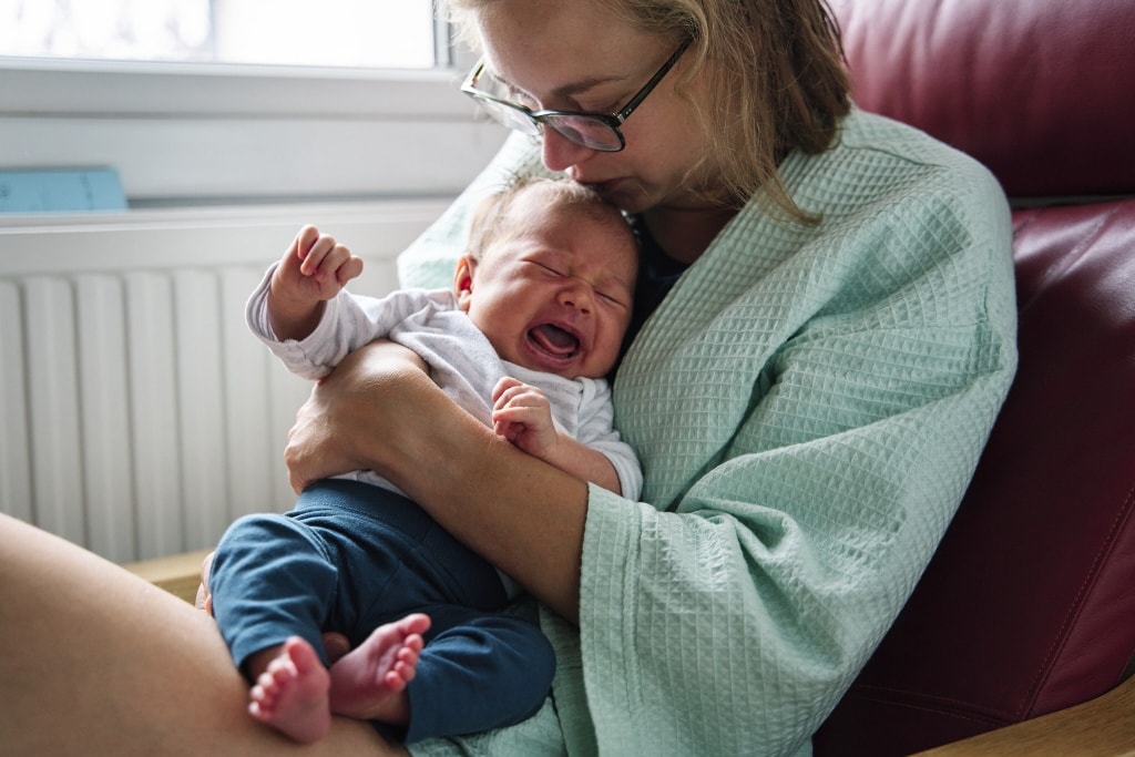 Mother soothing crying newborn druing a family baby photography photoshoot in Bromley Kent