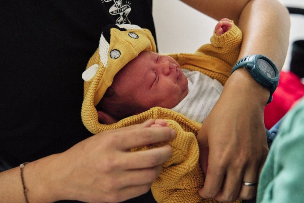 Close up of baby being dressed to go out during a documentary newborn photography session in Bromley.