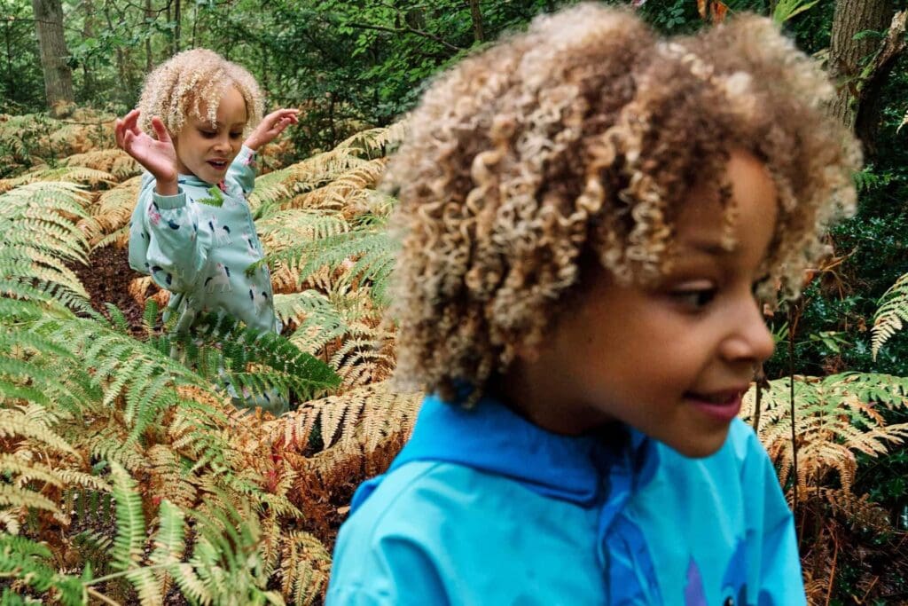 Girls walking through ferns at Hayes Common during a family photography session at Hayes Common in Bromley