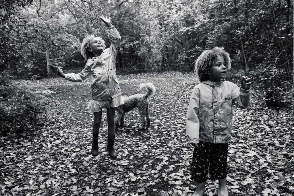 Girl jumping in the air to touch branches of a tree at hayes common during a photo session with Portray Your Story photography