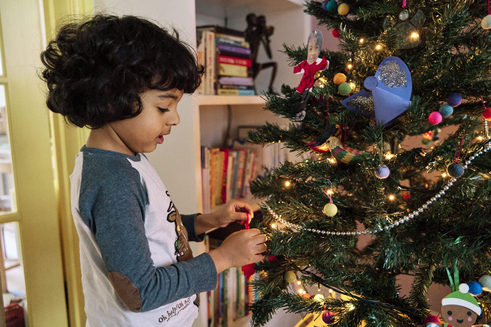 Close-up of child hanging Christmas bauble during documentary family photography session in South East London