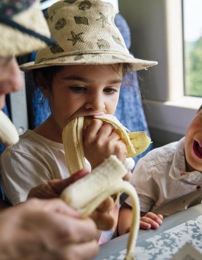 Family photographer photographing a family who are sitting on the train for a day at the beach.