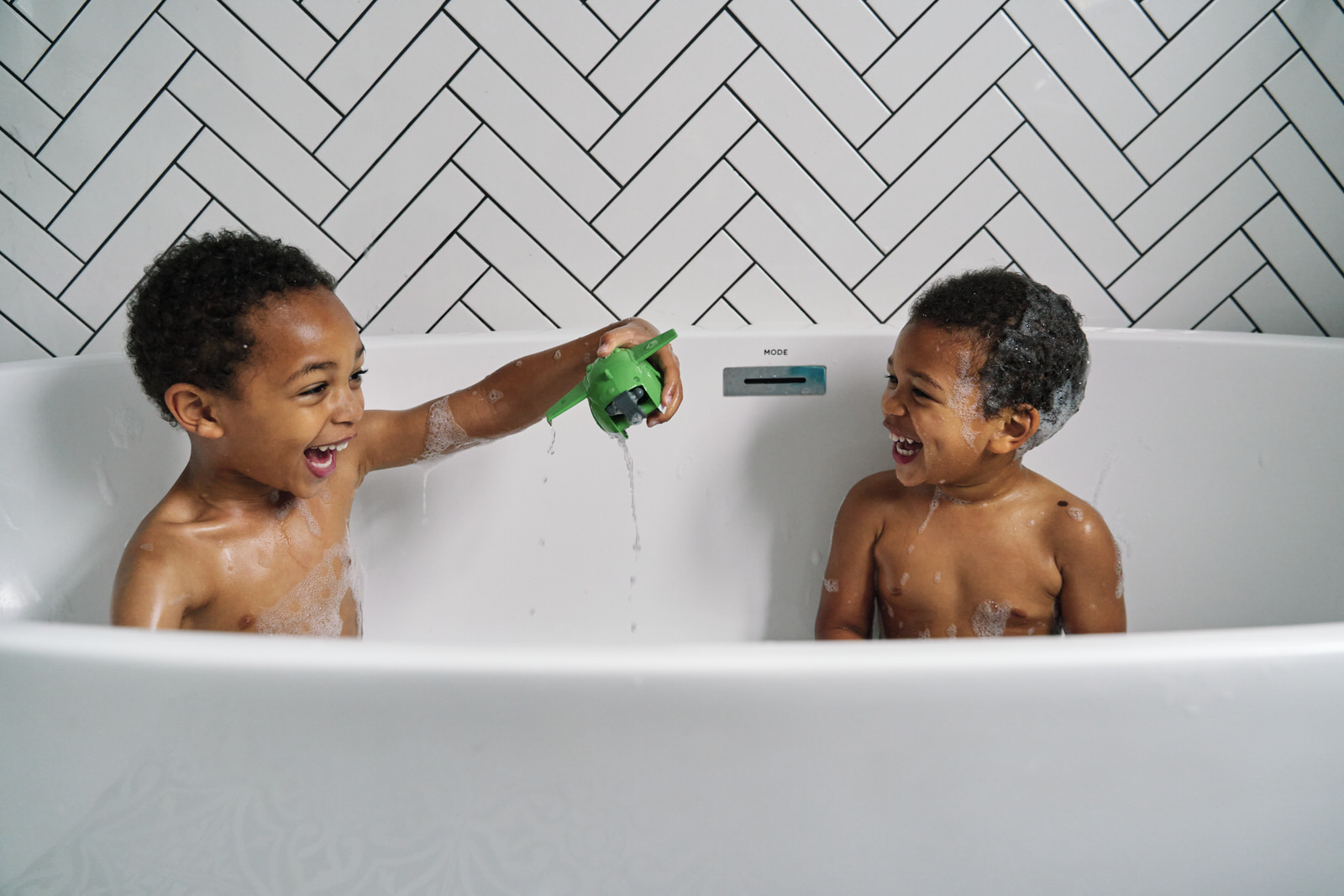 Family Photographer in London has taken a photo of siblings playing in the bathtub. 