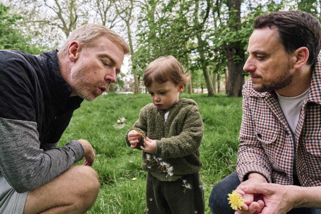 dads love and enjoy blowing dandelions with their son during London family photography