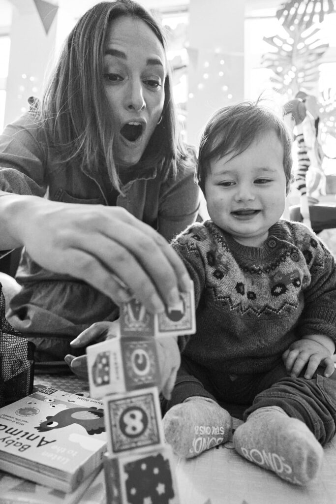 Photo of mother with child building a block tower together.