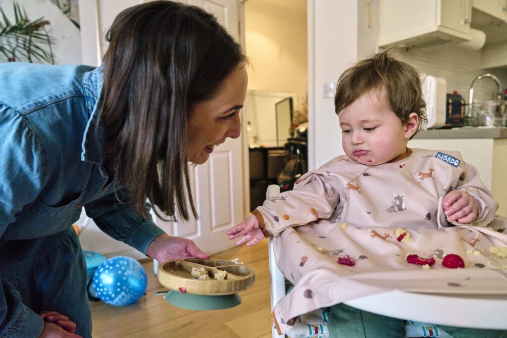 A mother giving food to her child in a family photo. 