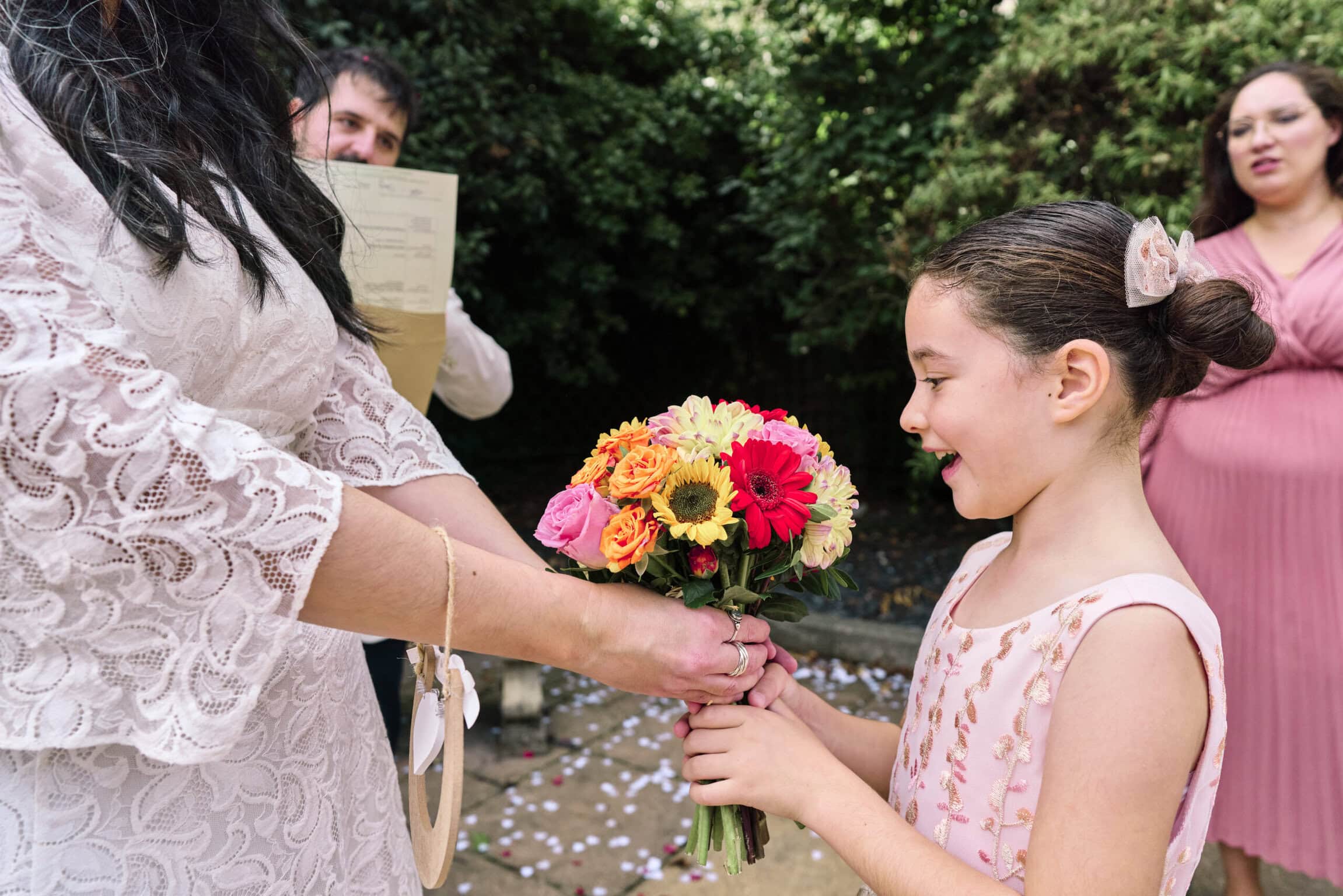Bride giving her bouquet to flowergirl during a quiet moment at an intimate London wedding.