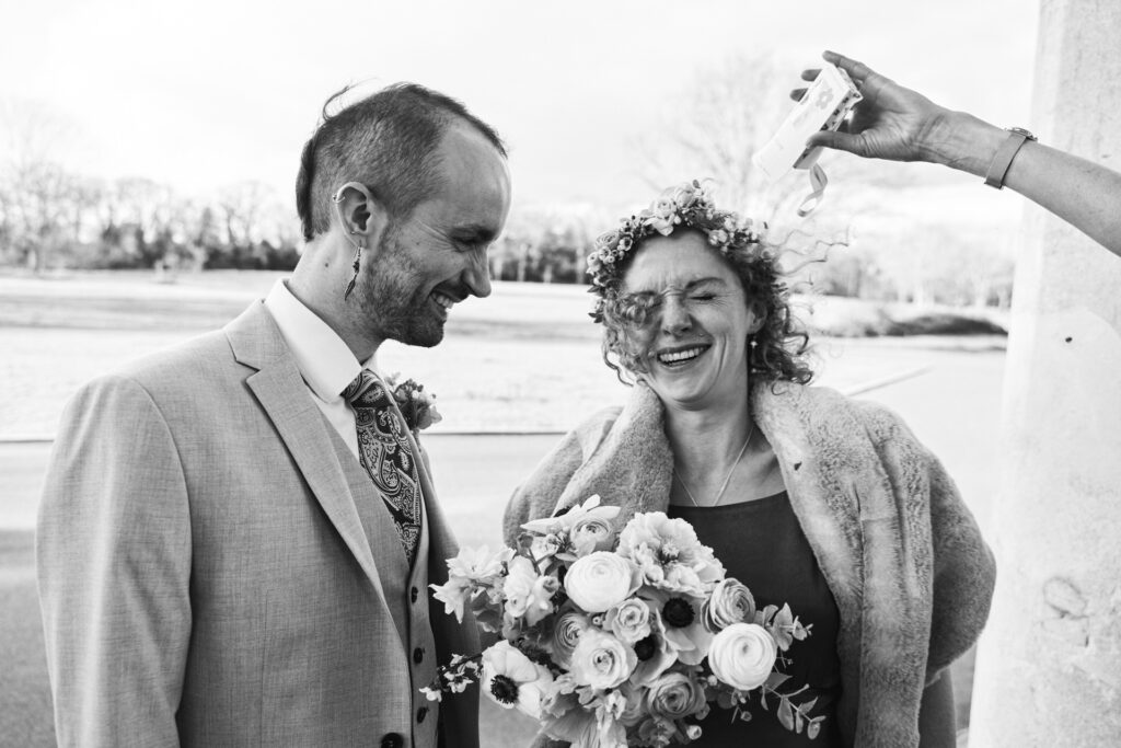 London documentary wedding photographer captures candid moment of throwing confetti on bride.