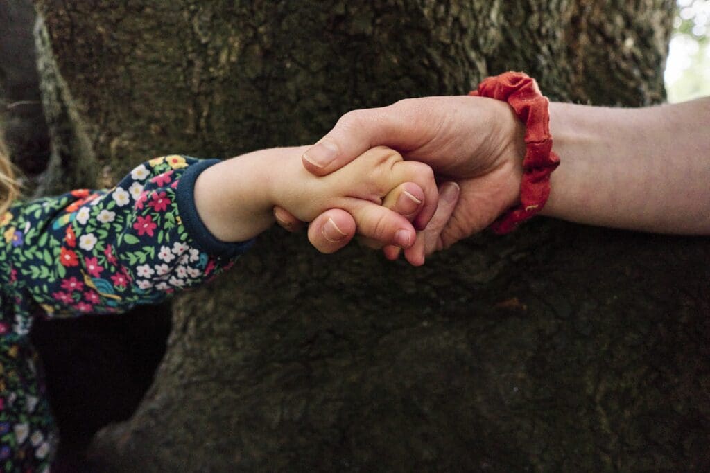 Documentary family photographer Saskia of Portray Your Story capturing real family life in London, this photo shows a close up of a mothers hand helping her child climb a tree.