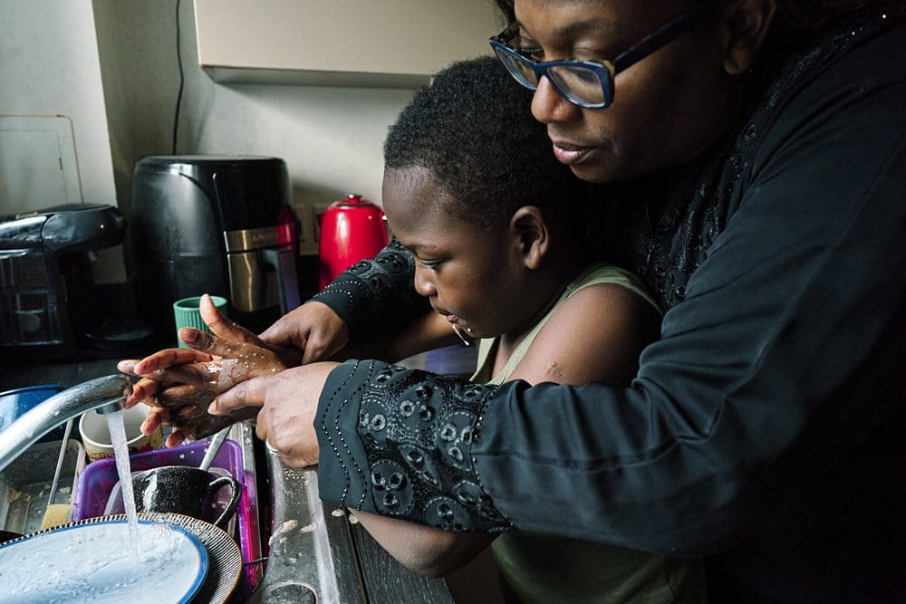 Documentary family photography session at home in London, natural and relaxed where a mum helps her autisitc child wash his hands.