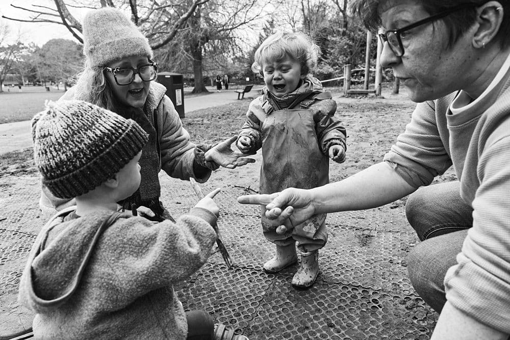 Boy crying about his stick being taken by a friend while his mums try to resolve it — real emotional documentary family photography Bromley
