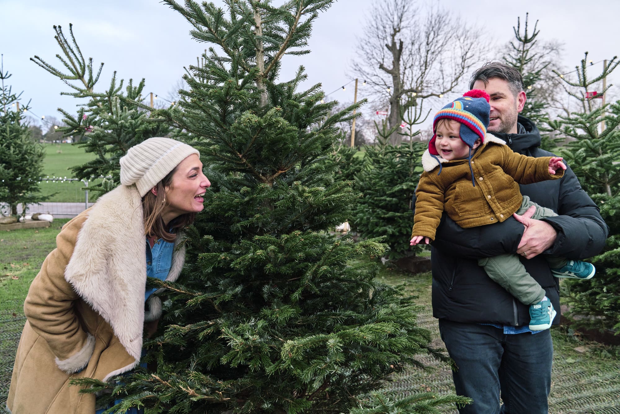 Family choosing a Christmas tree outdoors during South East London mini photography session