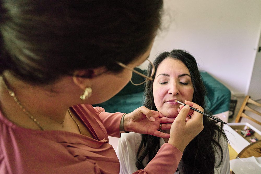 Bride putting on makeup before ceremony during documentary wedding in South East London