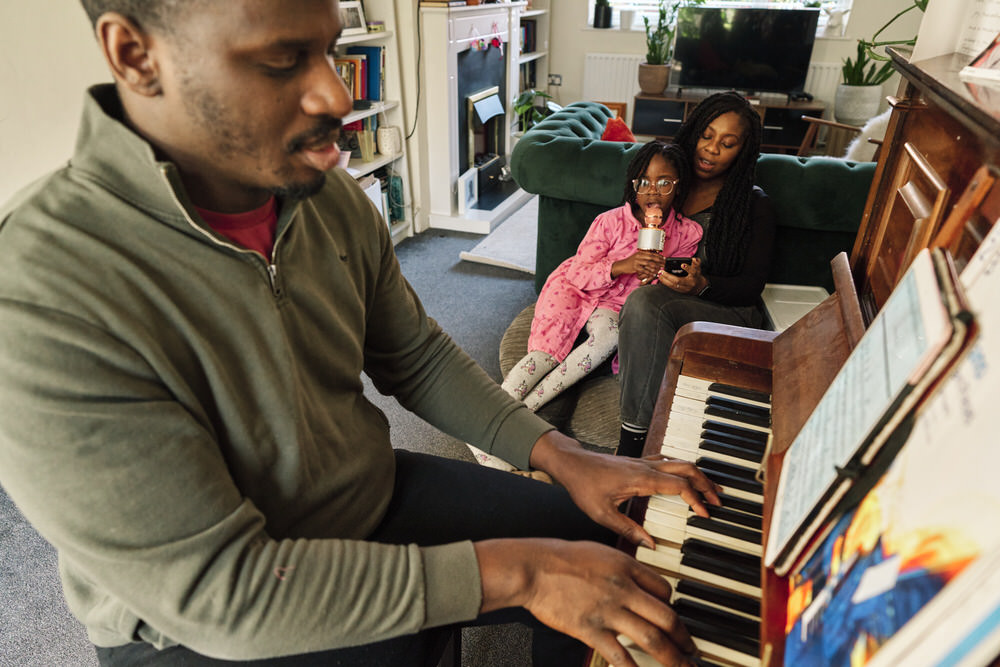Candid family making music together at home during documentary family photo session London.