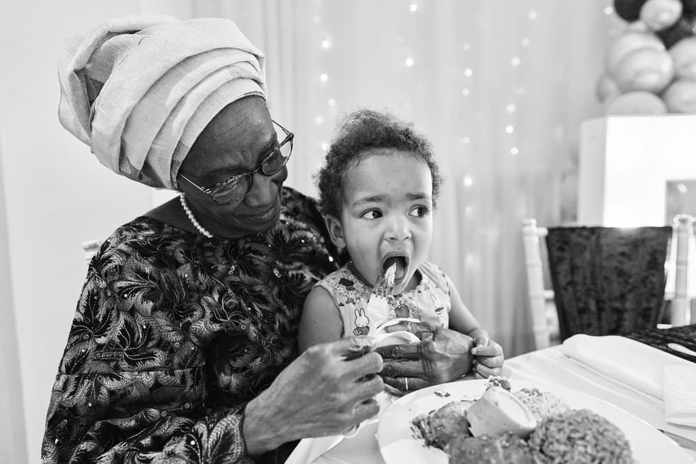 Reportage family event photography London - child being fed by grandparent during celebration dinner