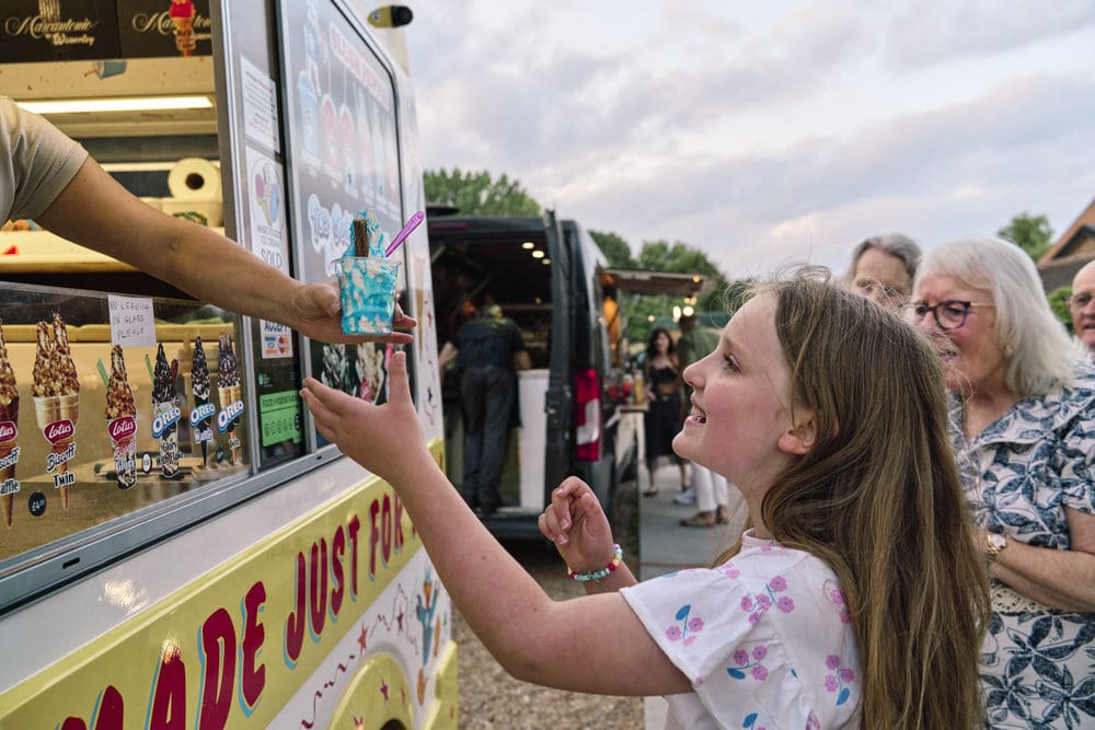 Honest family event photography in London capturing real details of family celebration of wedding anniversary party as a girl gets handed an ice-cream.